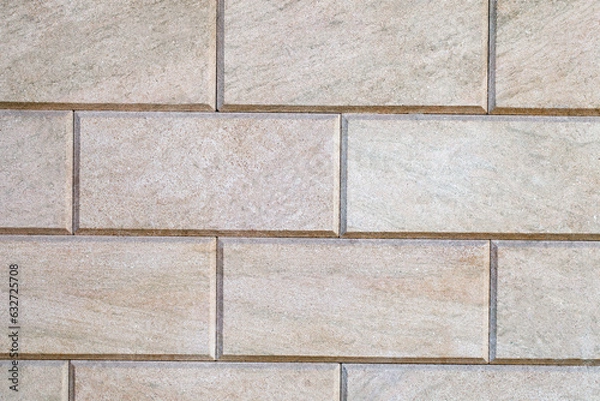 Fototapeta Wall is linked with decorative rectangular beige tiles, close-up, uniform texture background
