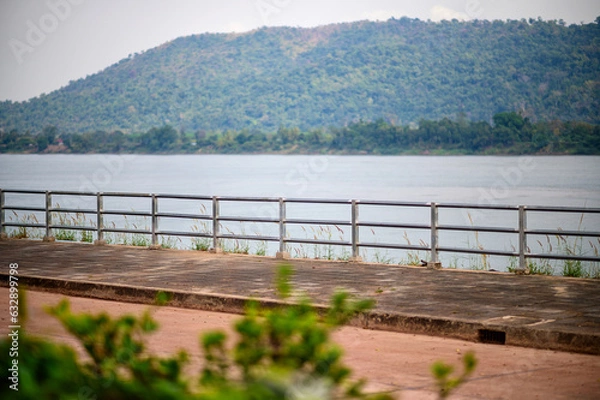 Fototapeta Scenic River Road with Mountain Backdrop: Serene Journey Along Iron Fence Divide