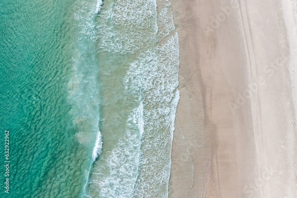 Fototapeta Aerial view of a beach with gentle waves and swimmers 