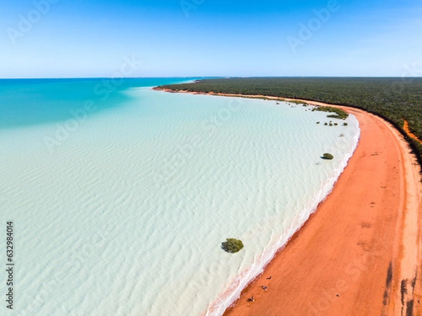 Fototapeta Aerial view of red sandy coastline along turquoise water at Red Sand Beach, Roebuck Bay, Broome, Western Australia