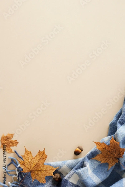 Fototapeta Enchanting fall aesthetic concept. Top view vertical arrangement of warm blanket, acorns, autumn maple leaves on pastel beige background with empty space for promo or message