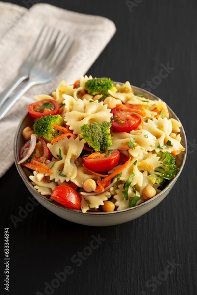 Fototapeta Yummy Homemade Vegan Pasta Salad with Tomato, Onion, Carrot, Broccoli, Chickpeas and Parsley in a Bowl, side view.