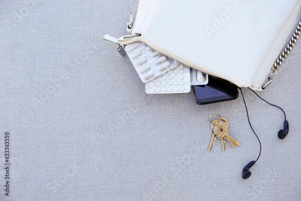 Obraz White handbag open with pills and women's accessories.