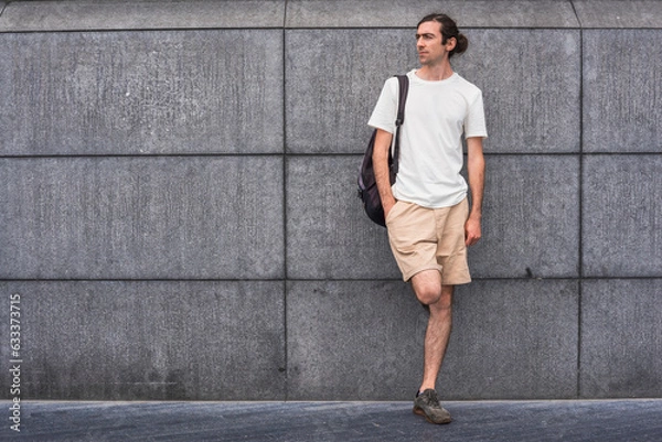 Fototapeta Handsome Young man  white t-shirt leaning against gray exposed concrete wall  background and wallpaper texture Modern loft empty cement. copy space city.