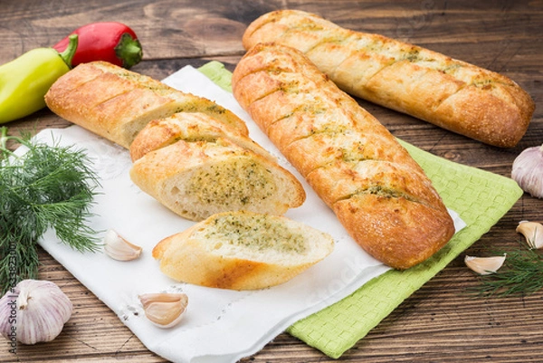 Fototapeta garlic baguette roll on a wooden cutting board