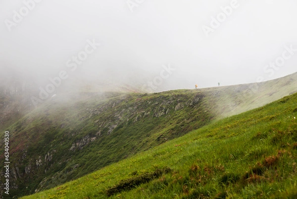 Fototapeta Two tourists climb a mountain in the fog
