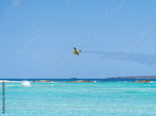 Fototapeta An aircraft releasing water while flying over the blue sea of Formentera