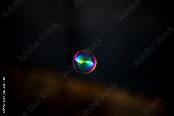 Fototapeta Colorful gold soap bubble on blurred dark background. Close-up.