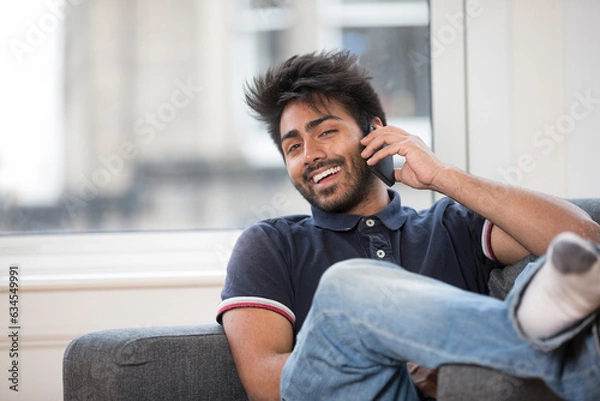 Fototapeta Indian Man using his phone at home.