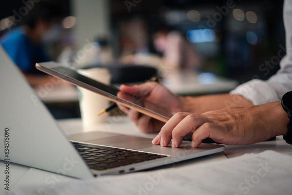 Fototapeta Man or Creative Freelancer working on Laptop and tablet at Office Desk. Business Technology, communication, and global networking Innovation, collaboration, and success in the digital world