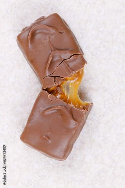 Obraz Chocolate bar with caramel fillings. Sweet chocolate bar broken into two pieces. Top view.