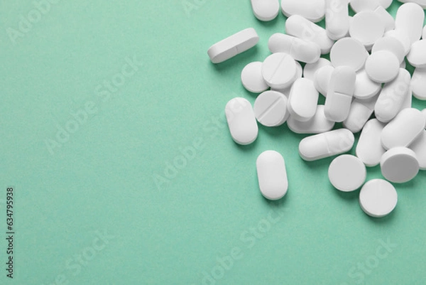 Fototapeta Pile of white pills on green background, flat lay. Space for text