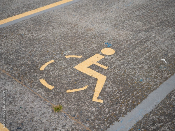 Fototapeta A wheelchair symbol is painted on the street. It marks a parking lot for disabled people.
