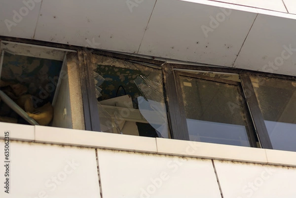 Fototapeta broken glass in windows, building damaged by war drones. Civil infrastructure destroyed by unmanned aerial vehicles. Tettorism and war aftermath