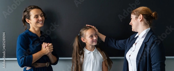 Fototapeta The teacher praises the schoolgirl in front of her mother standing at the blackboard. 