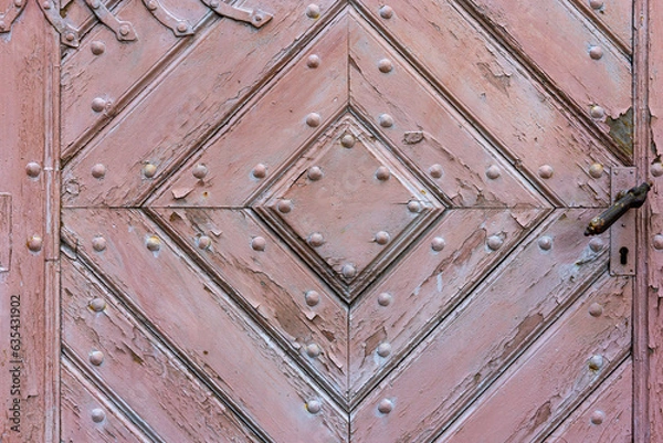Fototapeta Close-up of an old, church wooden door with a handle and keyhole. The door is made from planks of wood that have been weathered by the elements over time, giving it a rustic look.