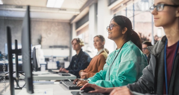 Fototapeta Portrait of a South Asian Female Student Studying in College with Diverse Classmates. Indian Girl Listening to Teacher, Using Computer to Apply Her Knowledge to Acquire New IT Skills in Class