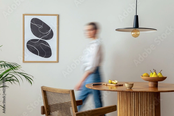 Obraz Interior design of domestic dining room space with two mock up poster frames, round table, chair, pedant lamp, decoration and woman in jeans. Minimalist home decor. Template.