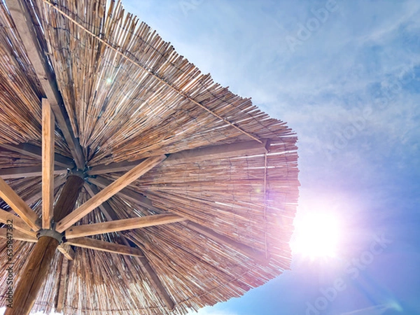 Fototapeta Beach straw umbrella against the background of the summer sky.