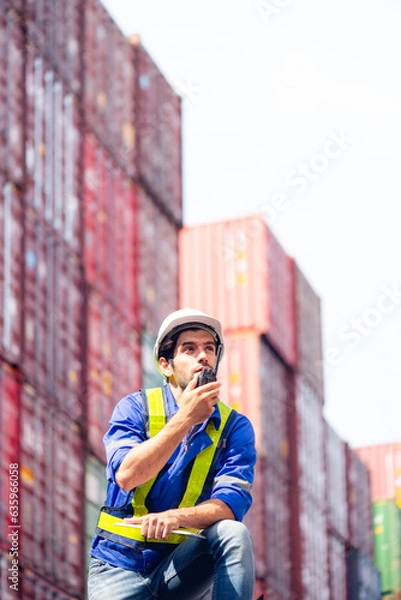 Fototapeta Portrait of Engineers or industrial workers using walkie-talkie command, communicate to shipping cargo freights colleague with background of cargo containers at shipping container yards and port yards