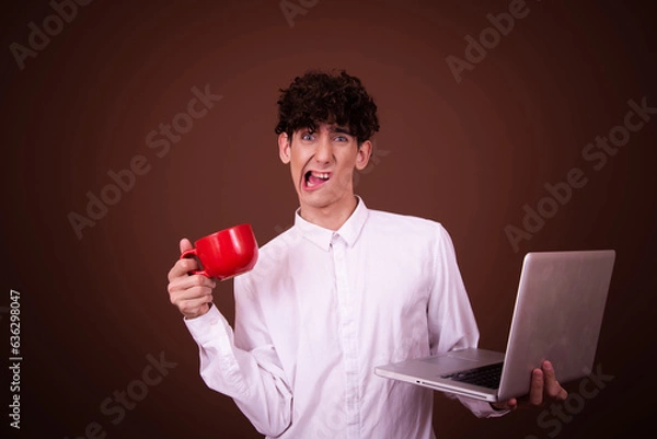 Fototapeta Funny young guy posing in the studio on a brown background. Study and work.
