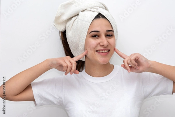 Fototapeta young latin woman with white towel on her head white t-shirt and white background gesturing happiness