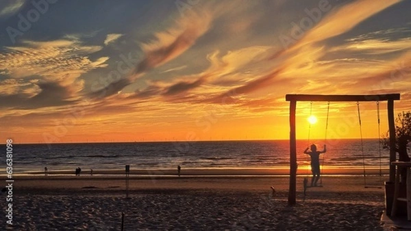 Fototapeta sunset on the beach of netherlands with swinging child