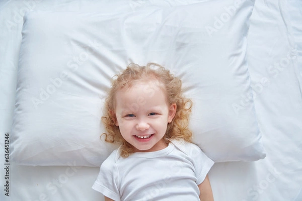 Obraz Smiling cute girl on a white pillow. Copy space