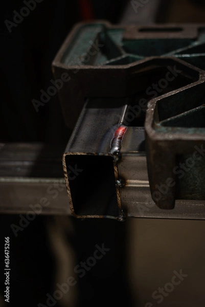 Fototapeta Red and hot weld seam between two square iron pipes clamped in special holders