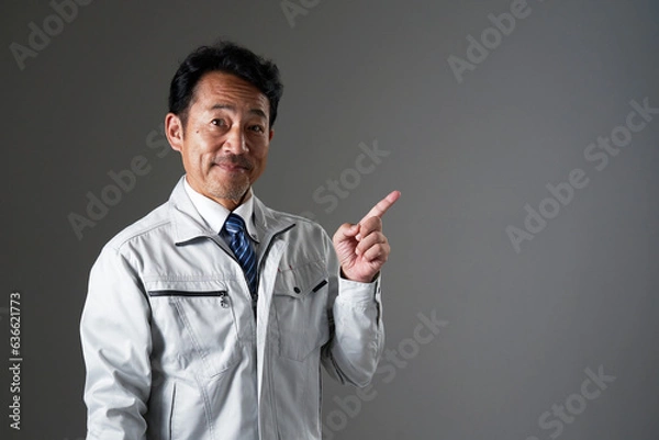 Fototapeta 右側を指差すミドルエイジの作業員　黒背景