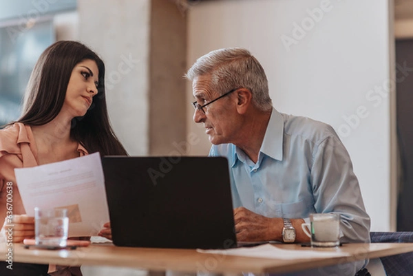 Fototapeta Focused experienced mature businessman giving training to young business client at corporate office workshop