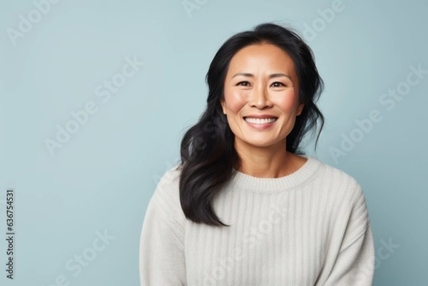 Fototapeta Portrait of a Chinese woman in her 40s in a pastel or soft colors background wearing a cozy sweater