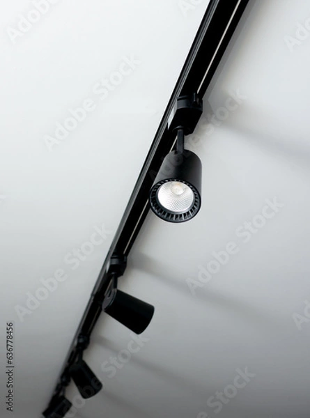 Obraz Led track lamp on the ceiling in the interior. Interior spotlight in black color. Modern track lamp with many rotary lamps