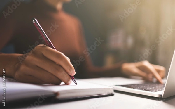 Fototapeta Woman hands using pen to list orders and sell products online and use Laptop typing on keyboard.
