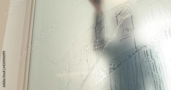 Fototapeta A man pastes a frosted coating on a glass door in a clinic to make the glass door opaque. Applying a matte coating to the glass.
