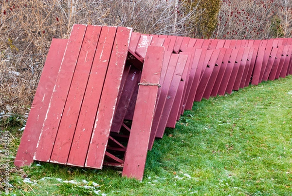 Obraz Red picnic tables stacked for winter storage in park.