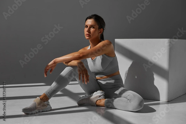 Fototapeta Athletic woman in sportswear doing stretching exercises in the gym. The concept of sports and recreation. healthy lifestyle