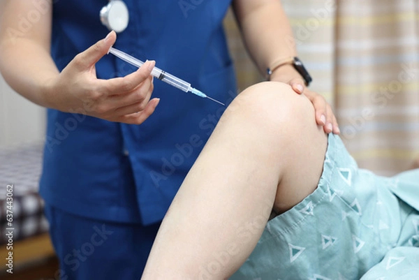 Obraz 병원에서 의사가 환자의 아픈 무릎에 주사를 놓는 모습