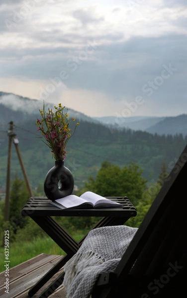Fototapeta Opened book on a table with flowers vase on mountain view