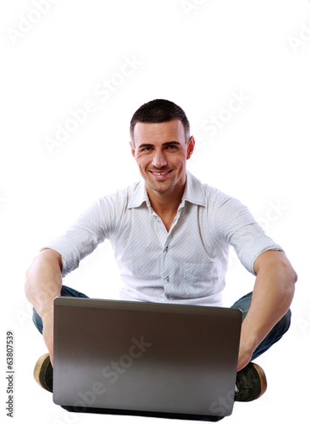 Fototapeta Cheerful man sitting at the floor with laptop 