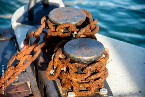 Fototapeta Old abandoned anchor chain with rust and iron cleat,  on a post in a sea dock
