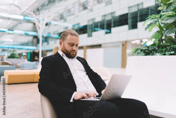Obraz Focused businessman working on laptop in spacious hall