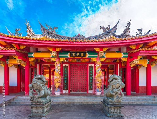 Fototapeta nagasaki, kyushu - dec 13 2022: Red gate of the Japanese Confucius Shrine called Kōshi-byō adorned with golden dragons and fenghuang phoenix on it and protected by two chinese shishiko guardian lions.