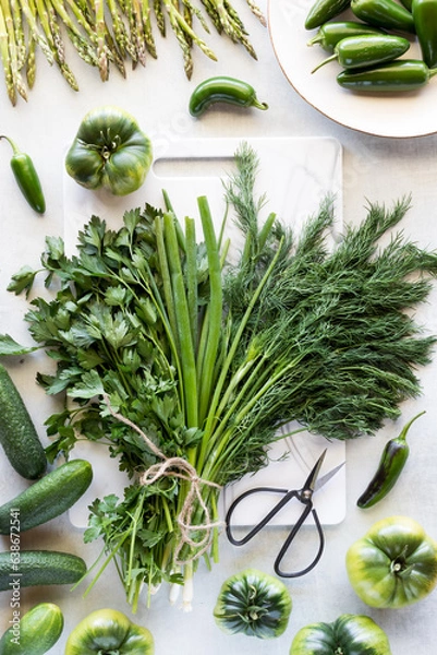 Fototapeta Bunches of herbs bound by twine and surrounded by green vegetables.
