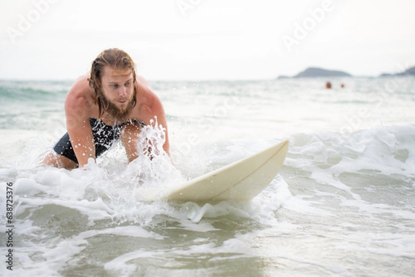 Obraz Young man surfing on the beach having fun and balancing on the surfboard