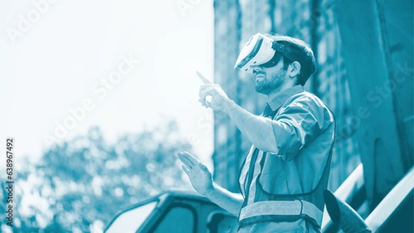 Fototapeta Engineer or technician worker wear PPE reflection cloth and virtual reality headset or VR glasses, acts like searching data in cloud database in desaturate tone. Logistic delivery by technology.