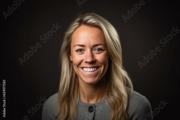 Fototapeta Portrait of a beautiful blond woman smiling at the camera on a black background