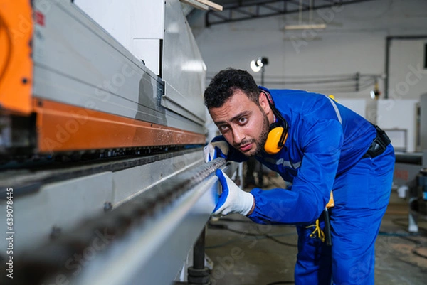 Fototapeta Male technician worker checking and repair pressing metal machine at factory, Machine maintenance technician operation concept.