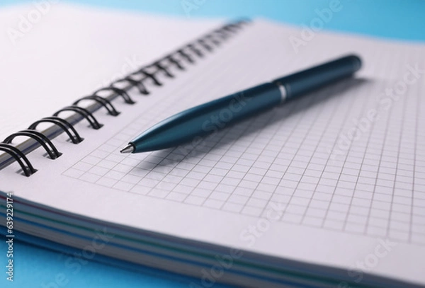 Fototapeta Empty white notebook with pen lie on table. Learning and education concept