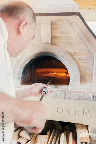 Obraz A talented French chef places a cheese and sausage pizza into the hot oven for 5 minutes
